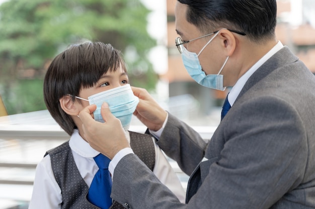 Foto grátis pai colocando uma máscara protetora no filho, família asiática usando máscara facial para proteção durante a quarentena. coronavírus covid 19 surto