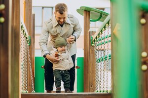 Foto grátis pai com filho bebê no campo de jogos se divertindo