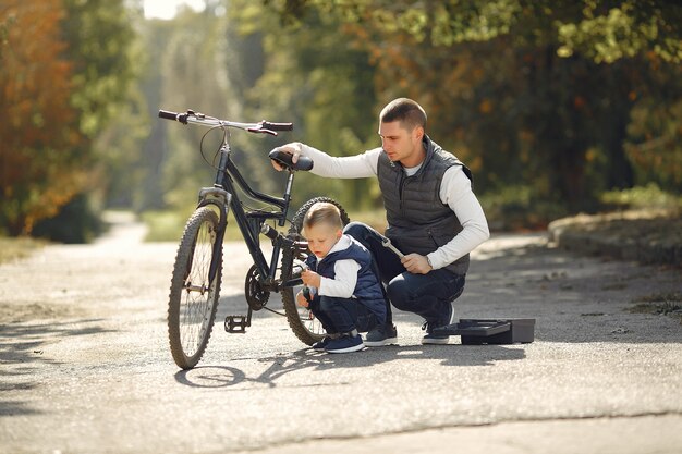 Pai com filho repare a bicicleta em um parque