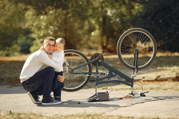 Pai com filho repare a bicicleta em um parque