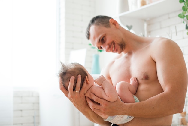 Pai, com, pelado torso, segurando bebê