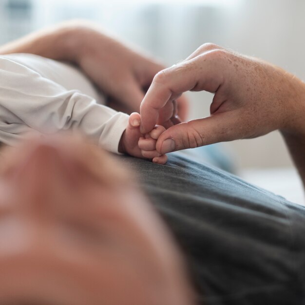 Pai de close-up, segurando a mão do bebê