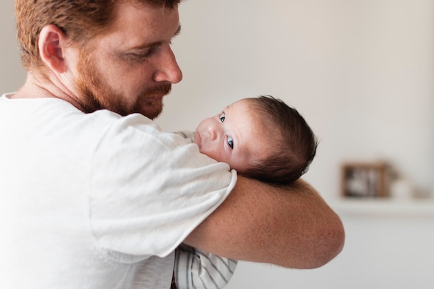 Foto grátis pai de close-up, segurando o bebê com olhos azuis