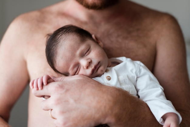 Pai de close-up, segurando seu bebê sonolento