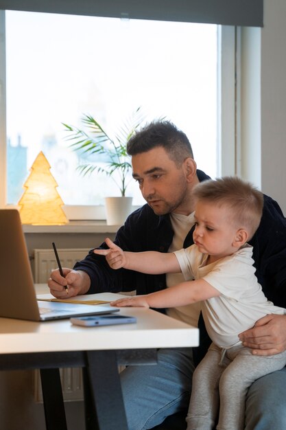 Pai de tiro médio a trabalhar com o filho em casa.