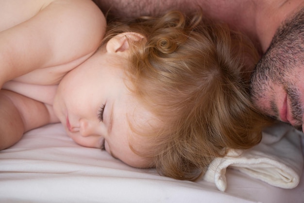 Pai e bebê dormindo na cama pela manhã a família dorme perto do retrato de crianças sonolentas Foto Premium
