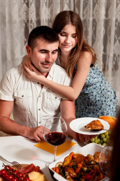 Pai e filha abraçados na mesa de jantar