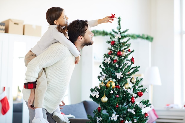 Foto grátis pai e filha felizes decorando a árvore de natal