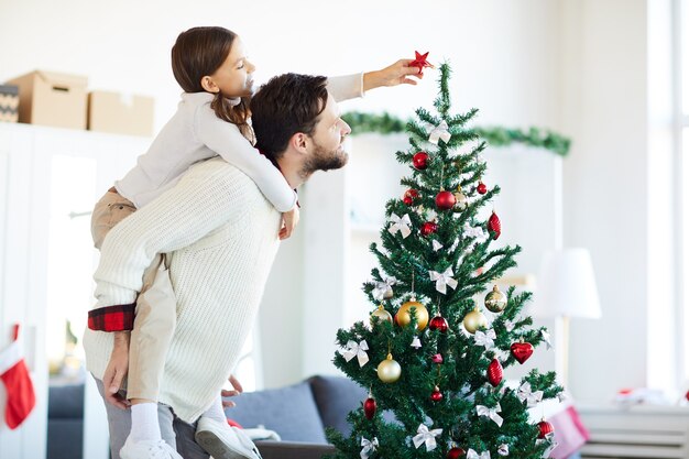 Pai e filha felizes decorando a árvore de Natal