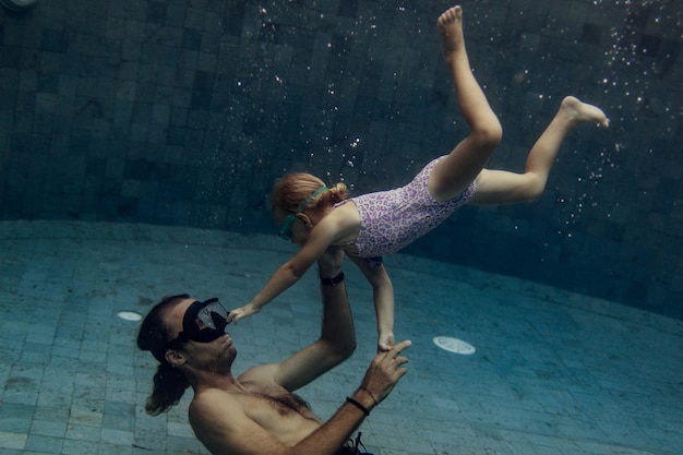 Pai e filha nadando juntos na piscina