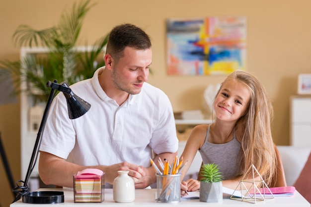 Pai e filha sorrindo e sentado em uma mesa