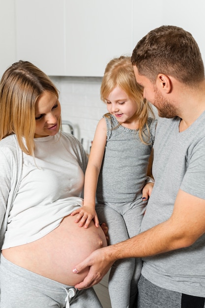 Pai e filha tocando a barriga da mãe