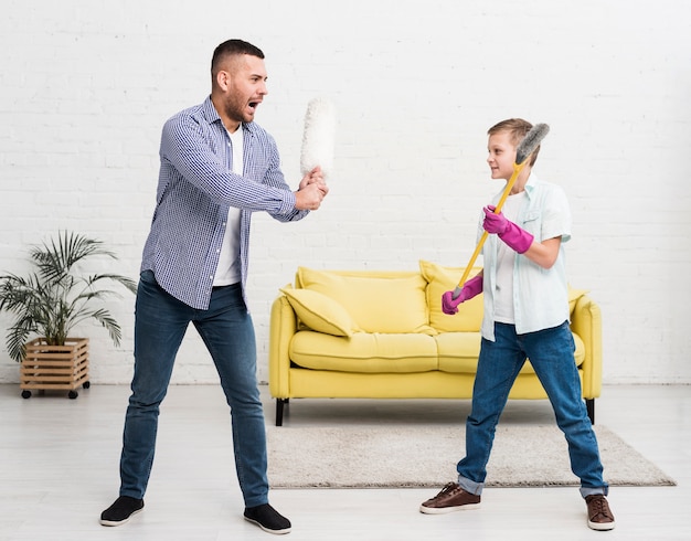 Foto grátis pai e filho brigam com espanador e vassoura