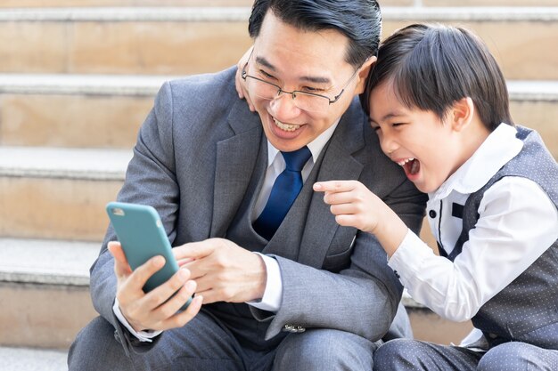 Pai e filho brincando de smartphone juntos no distrito comercial urbano
