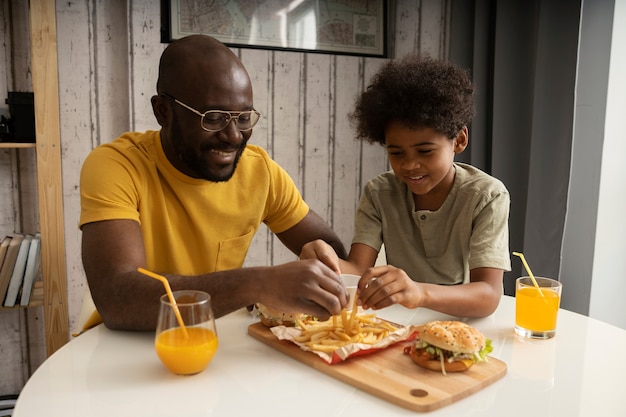 Pai e filho comendo hambúrgueres e batatas fritas juntos