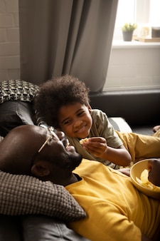 Pai e filho comendo lanches juntos no sofá