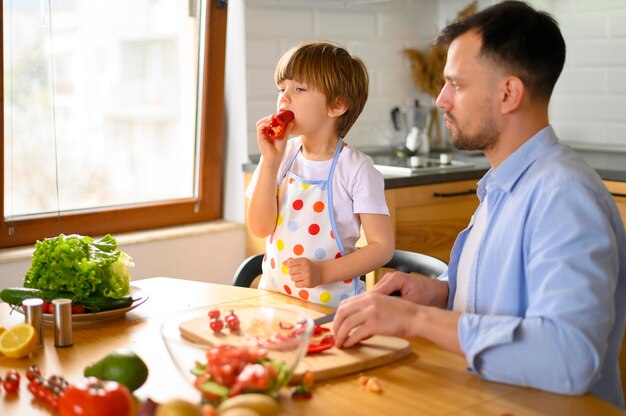 Pai e filho comendo vegetais frescos