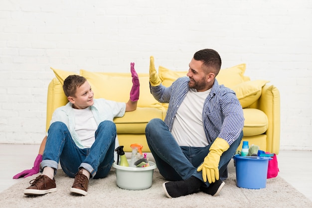 Foto grátis pai e filho cumprimentando um ao outro durante a limpeza