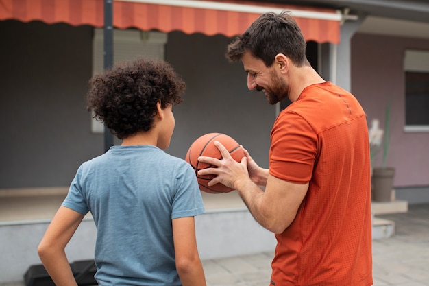 Foto grátis pai e filho jogando basquete juntos no quintal