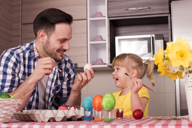 Pai e filho pequeno pintando os ovos de páscoa