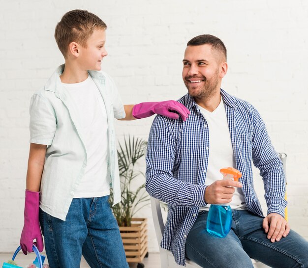 Pai e filho posando enquanto seguram produtos de limpeza