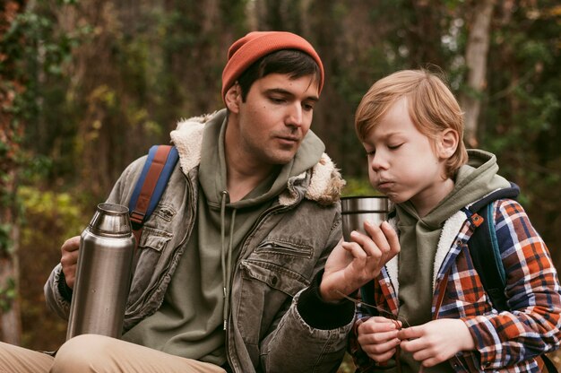 Pai e filho tomando chá quente ao ar livre na natureza