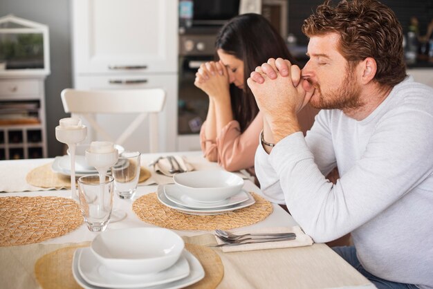 Pai e mãe rezando juntos em casa