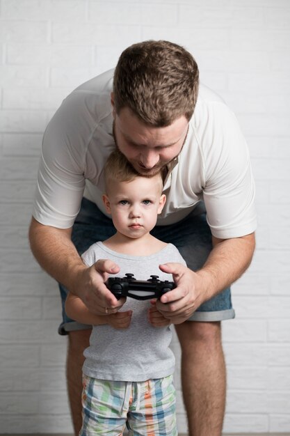 Foto grátis pai ensinando filho a brincar com joystick