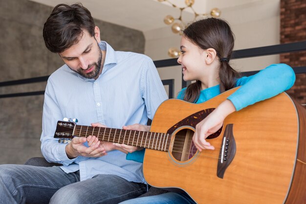 Pai ensinando menina a tocar violão