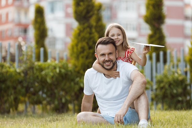 pai feliz brincando com aviões filha ao ar livre