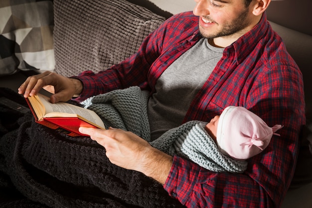 Foto grátis pai feliz com o livro de leitura do bebê na noite