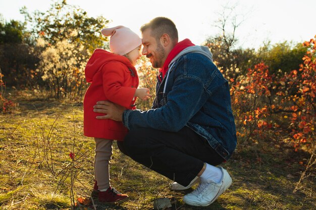 Pai feliz e filha pequena caminhando pelo caminho da floresta em um dia ensolarado de outono