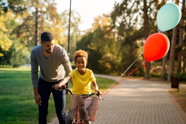 Pai feliz ensinando sua linda filha a andar de bicicleta no parque