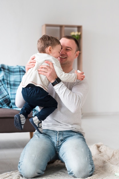 Foto grátis pai feliz, segurando o filho em casa