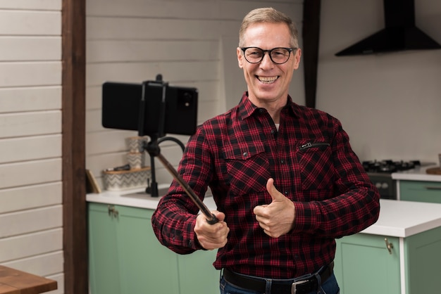 Pai feliz, sorrindo e tomando uma selfie, dando polegares para cima