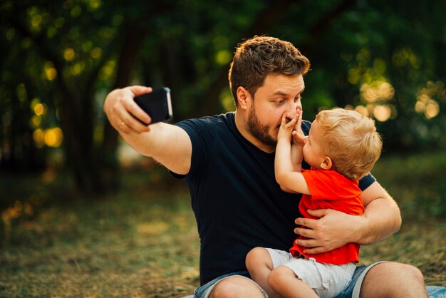 Pai, levando, um, selfie, e, tocando, com, seu, criança