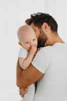 Foto grátis pai lindo segurando e beijando seu bebê