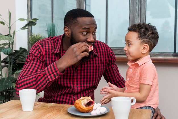 Pai negro e filho tomando café da manhã