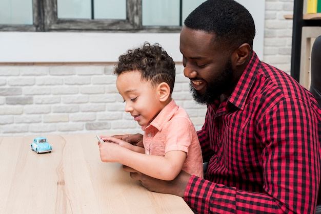 Foto grátis pai negro e filho usando tablet