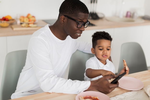 Pai olhando algo em seu telefone com seu filho