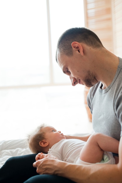 Foto grátis pai, segurando, bebê joelhos