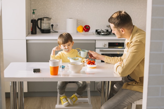 Foto grátis pai segurando o copo para o filho beber