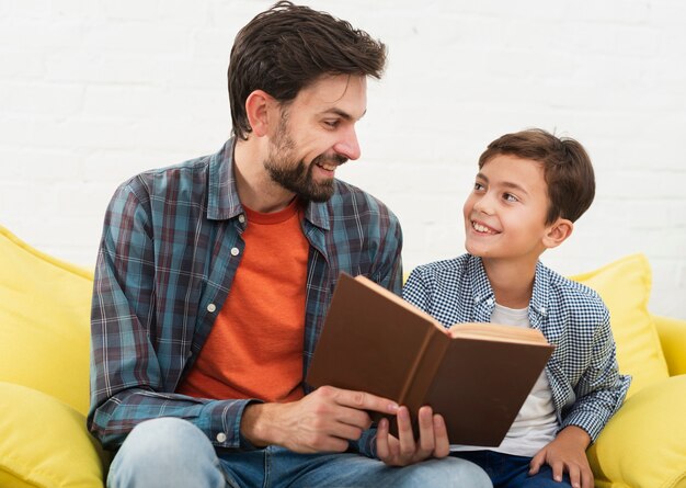 Pai segurando um livro e olhando para seu filho