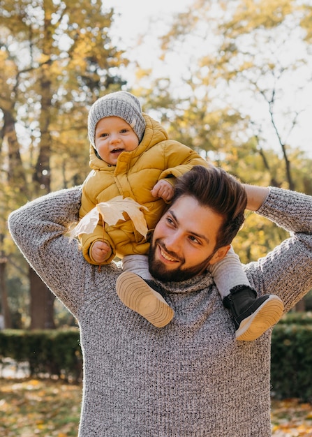 Pai sorridente com seu bebê ao ar livre