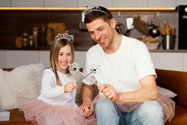 Pai sorridente e filha brincando com tiara e varinha