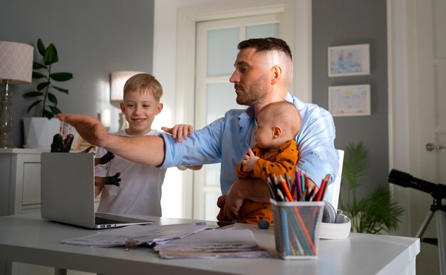 Pai trabalhando em casa tentando equilibrar vida familiar com filho e trabalho