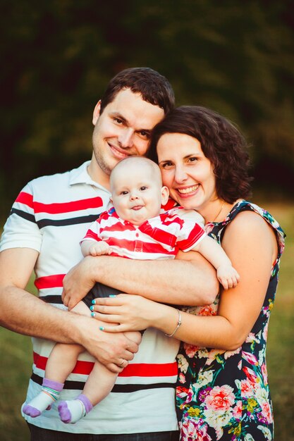 Pais alegres sorriem para o filho pequeno em seus braços