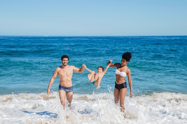 Pais brincando com criança no litoral