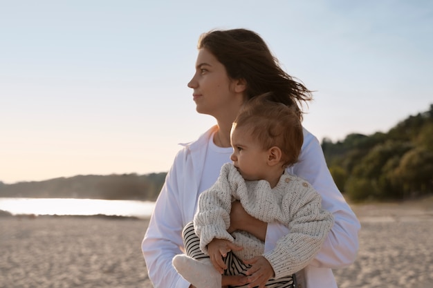 Foto grátis pais com um bebê na praia ao pôr do sol