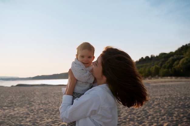 Foto grátis pais com um bebê na praia ao pôr do sol